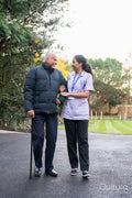 Care giver assisting senior man while walking outside nursing home