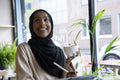 Smiling young woman in hijab drinking coffee in cafe
