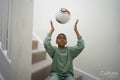 Boy sitting on stairs and throwing soccer ball in air