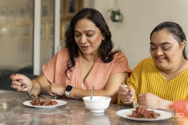 Mother eating dinner with down syndrome daughter at home