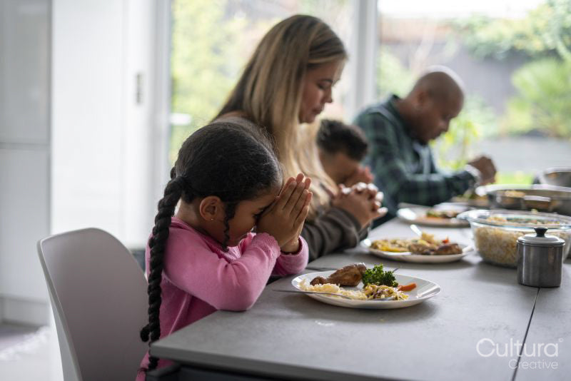 Family praying before eating dinner