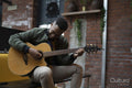 Young man playing acoustic guitar in office lounge