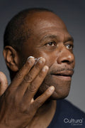 Portrait of man applying cream on face