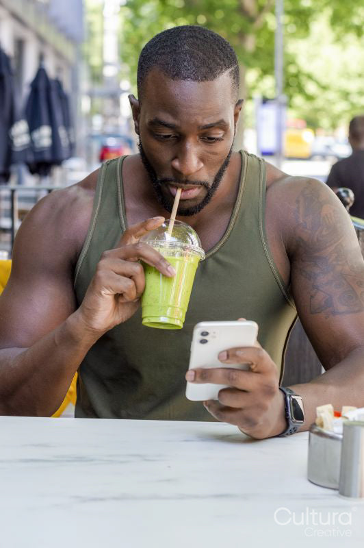 Mid adult man drinking smoothie and using smart phone