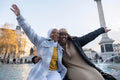 Smiling young female tourists in hijabs hugging in city square