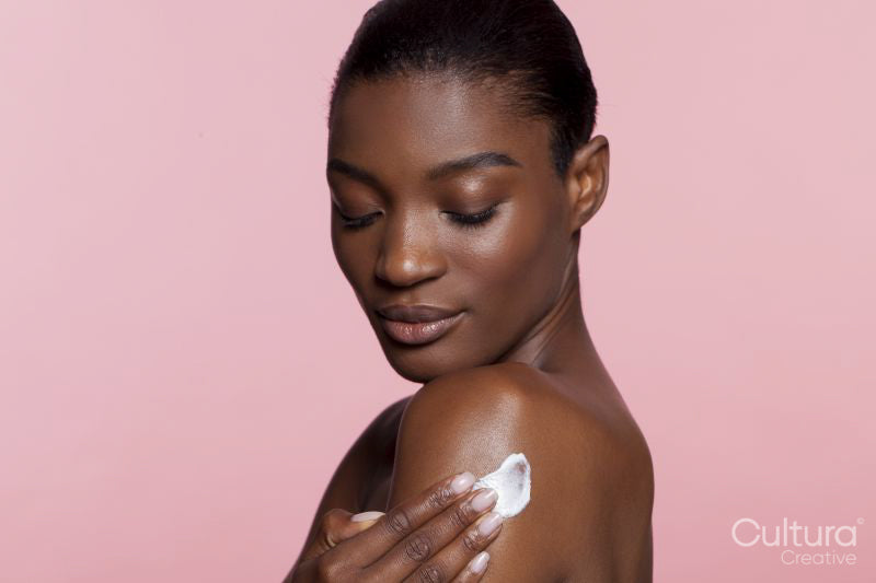 Young woman applying cream on shoulder
