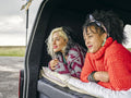 Women lying in back of van and looking at view