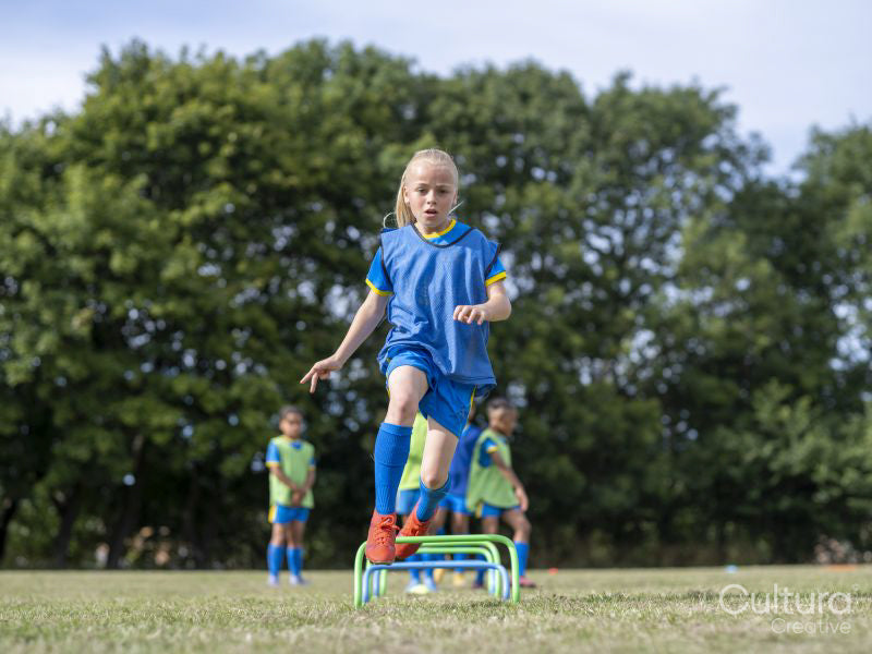 Children dressed in uniforms practicing on soccer field