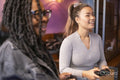 Female friends having fun while playing in video games at pub