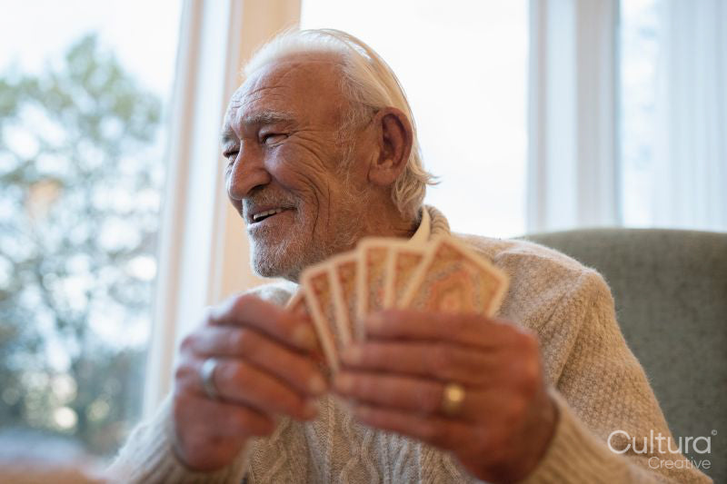 Smiling senior man playing cards at table