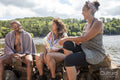 Smiling friends wrapped in towels sitting on lakeshore, Yorkshire, UK