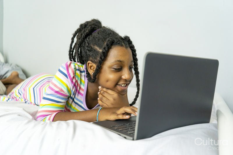 Girl lying on bed using laptop
