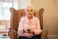 Senior woman sitting in armchair and using remote control