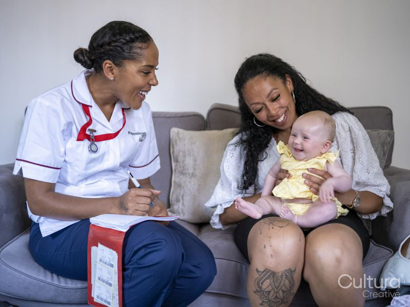 Nurse visiting woman with baby girl at their home
