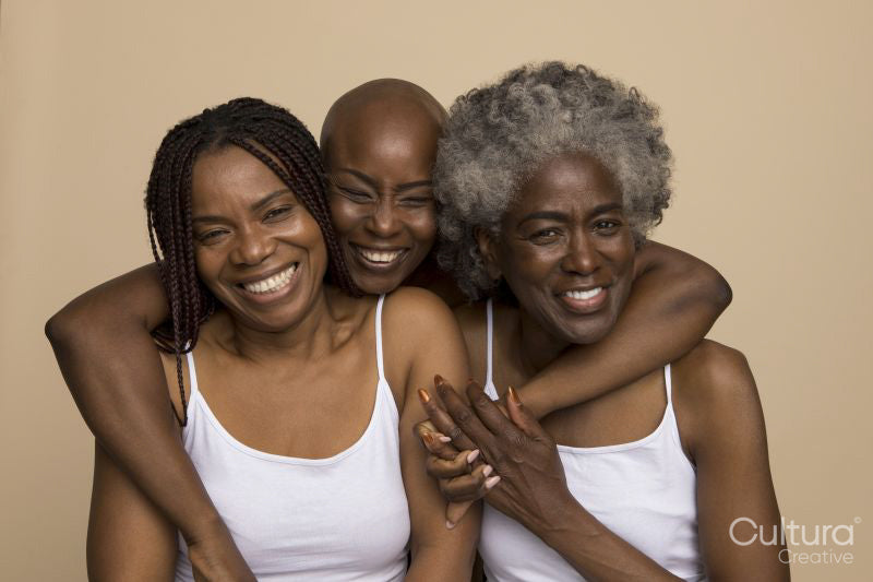 Studio portrait of three smiling women in white tops