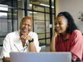 Two women sitting in office looking at laptop