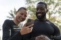 Smiling athletic man and woman looking at smart phone in park