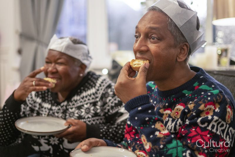 Senior couple sitting on sofa eating Christmas cookies
