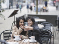 Smiling female couple taking selfie in sidewalk cafe
