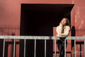Portrait of smiling woman leaning on railing against red wall
