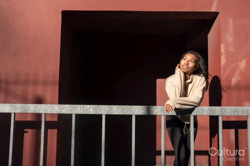 Portrait of smiling woman leaning on railing against red wall
