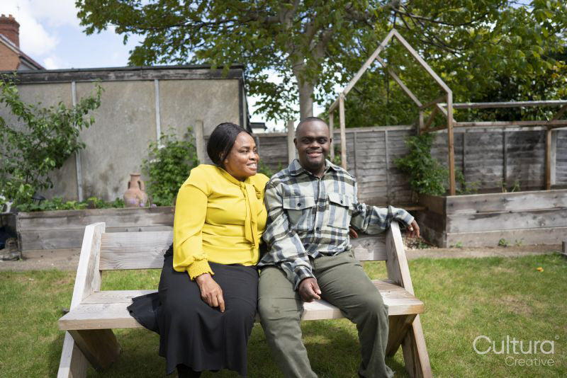 Mother and adult son with Down syndrome sitting on bench in garden