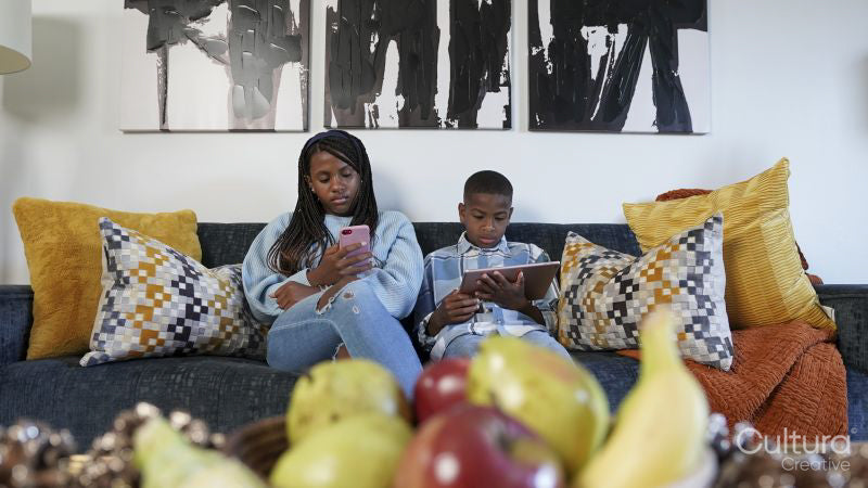 Siblings using tablet and smart phone at home