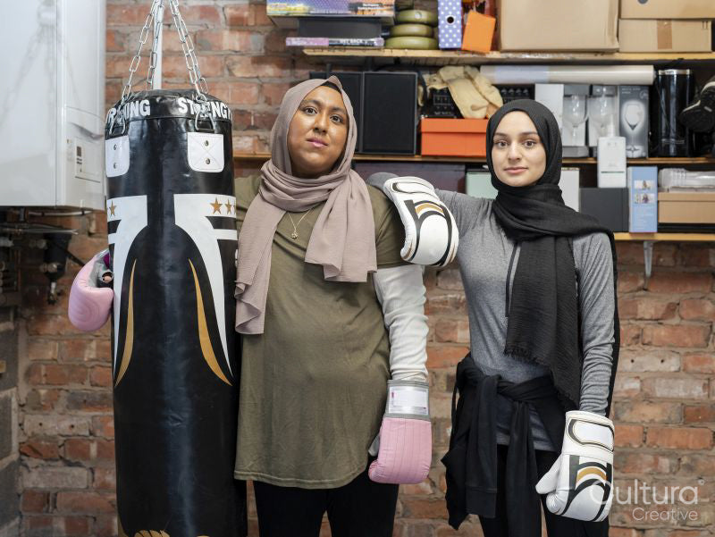 Two women standing in exercising facility during boxing training