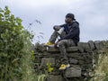 Young man sitting on stone wall holding bullhorn