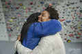 Mother with daughter embracing in front of climbing wall