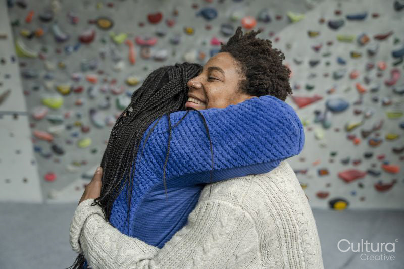 Mother with daughter embracing in front of climbing wall