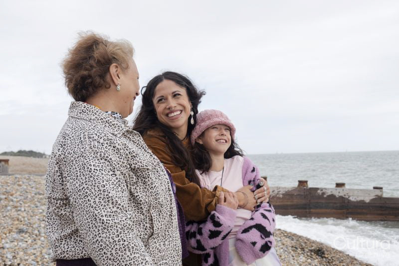 Grandmother, mother and daughter looking at sea on cloudy day
