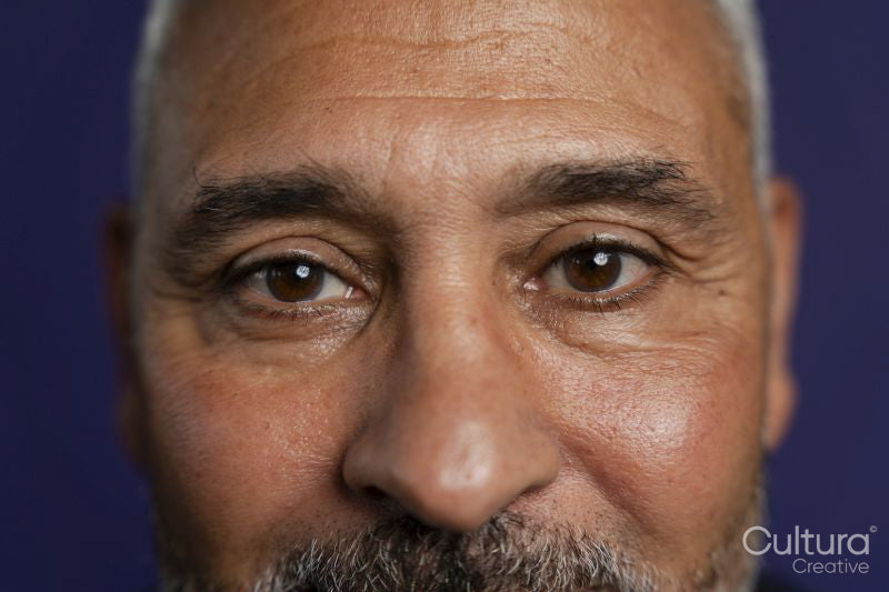 Close-up of man looking at camera against purple background