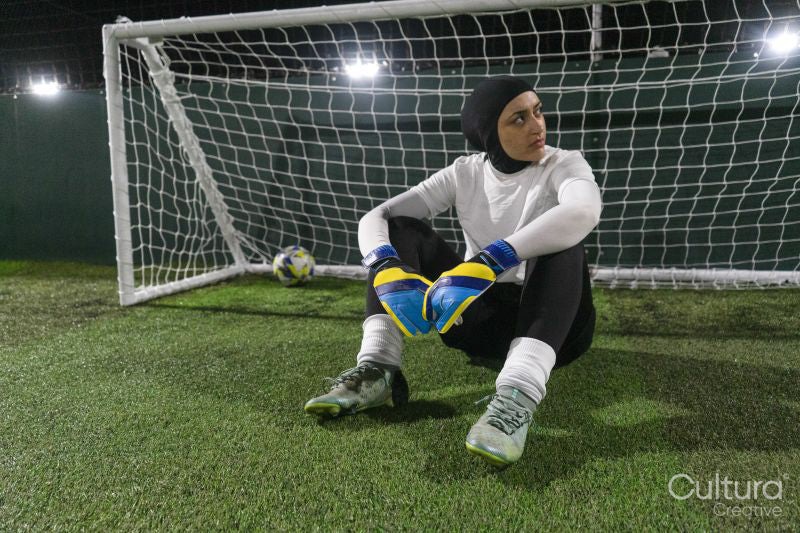 Female goal keeper sitting on ground