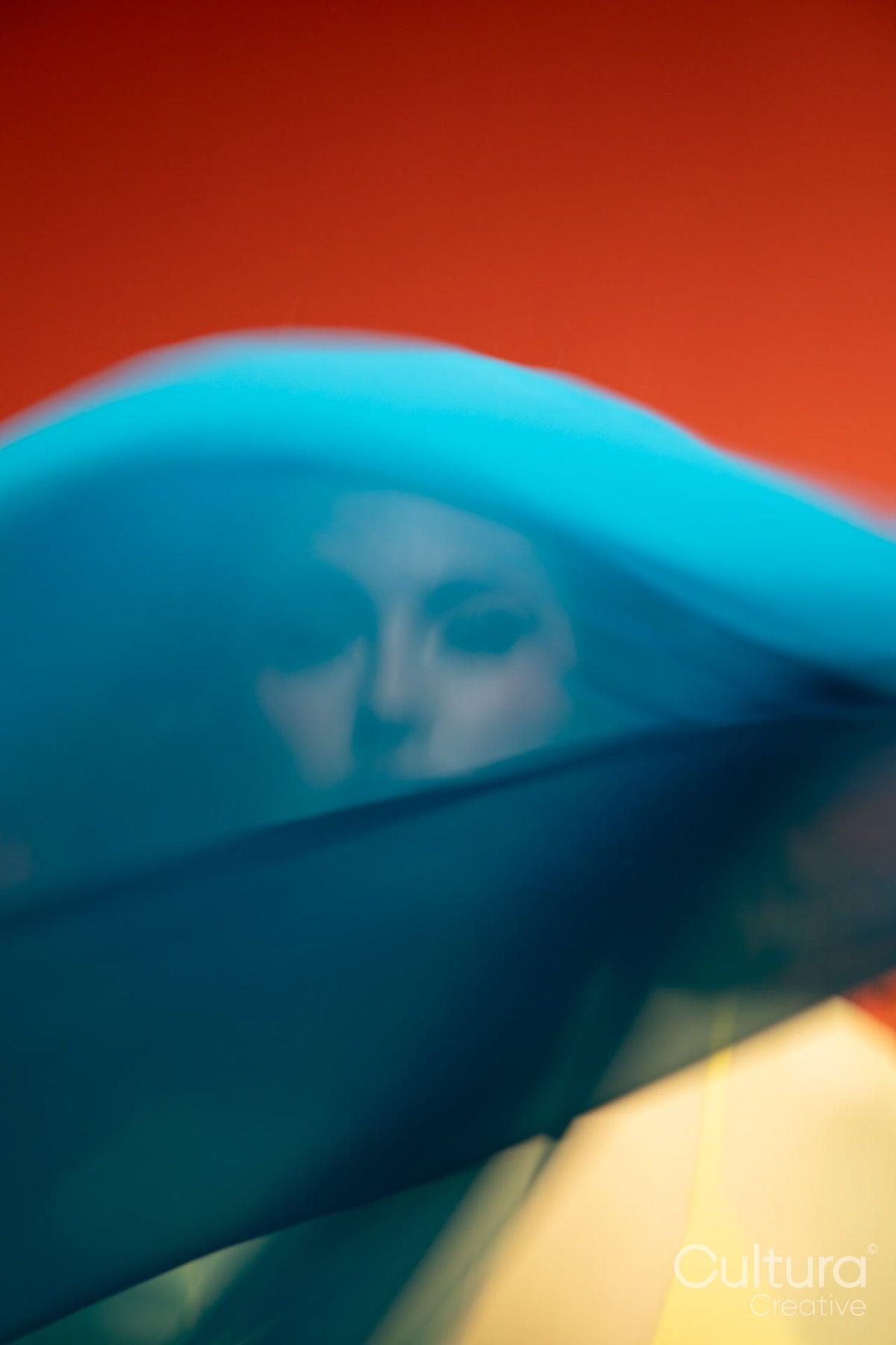 Woman in a yellow dress veiled by flowing blue fabric