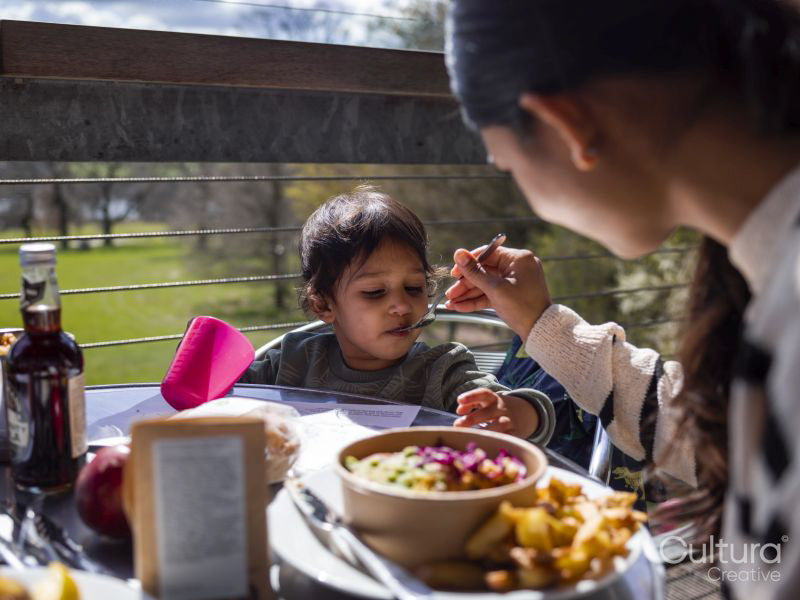 Mother feeding son at restaurant table