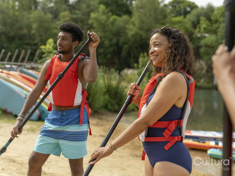 Friends warming up with oars on beach before paddleboarding
