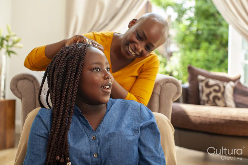Mother braiding hair for daughter
