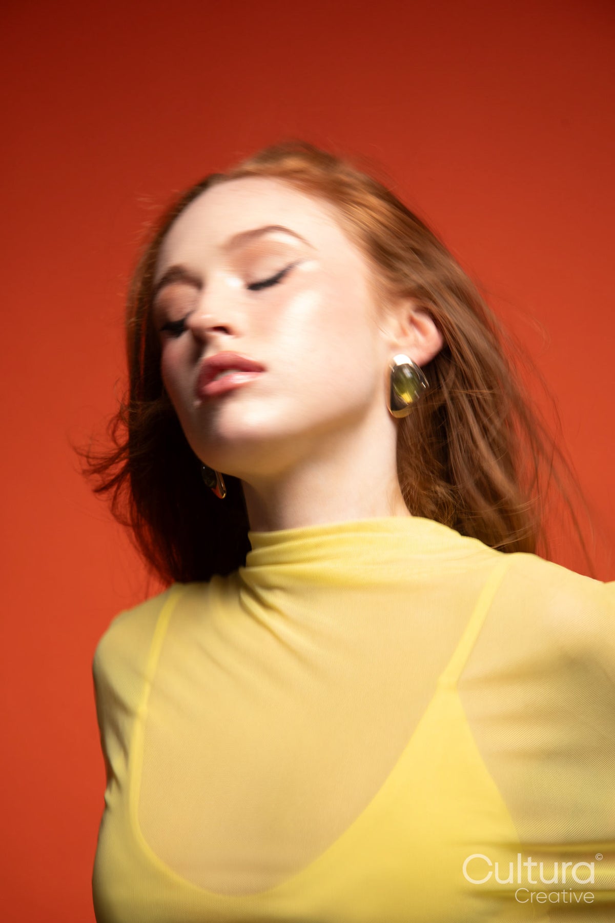 Woman in a yellow dress with windswept hair in a studio