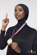 Studio portrait of young woman in hijab wearing gold medal