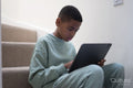 Boy sitting on stairs and using tablet