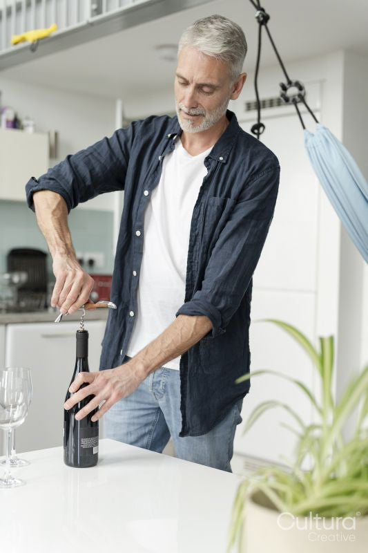 Mature man opening red wine at home