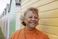 Portrait of smiling senior woman standing by beach hut