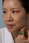Mid adult woman wearing pink eyeshadow and green ring
