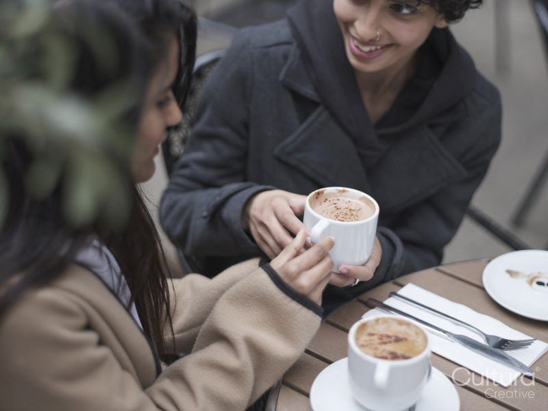 Female couple drinking coffee in sidewalk cafe