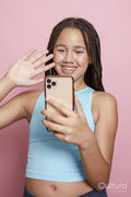 Studio shot of smiling girl with braids looking at smart phone