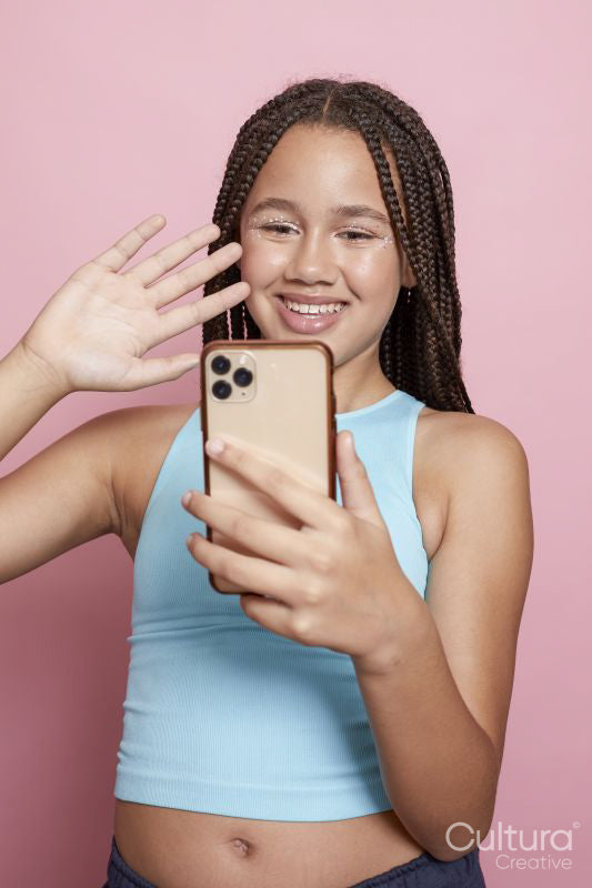 Studio shot of smiling girl with braids looking at smart phone