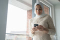 Smiling woman in hijab using smart phone
