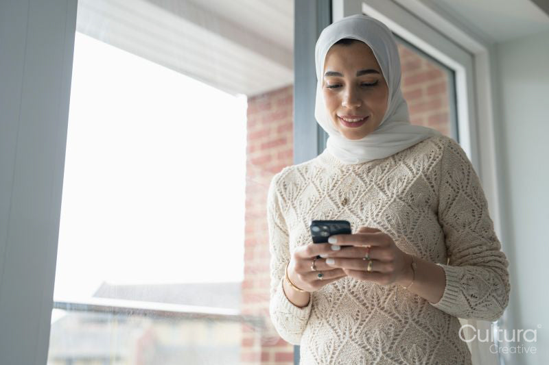 Smiling woman in hijab using smart phone