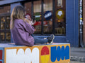 Woman taking selfie while sitting on wall in city